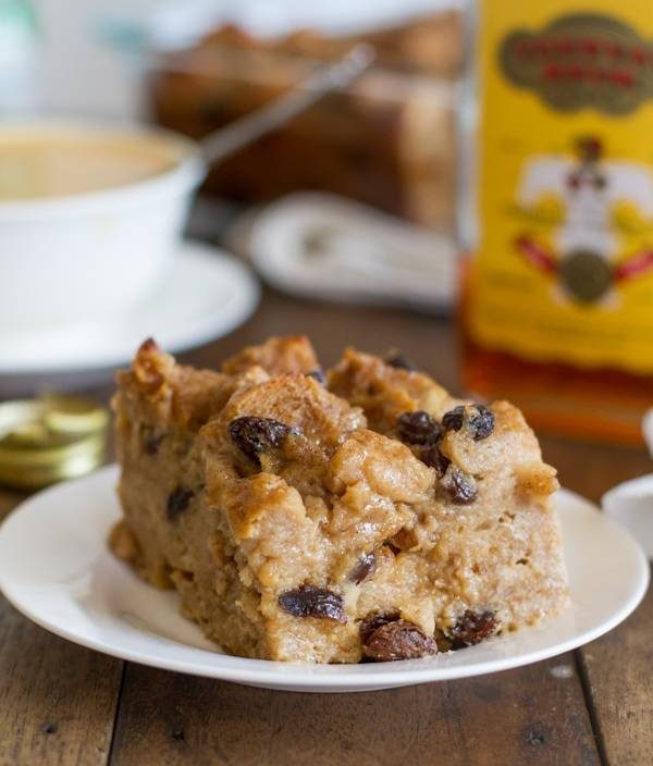 Bread pudding with hot butter rum sauce on a white plate.