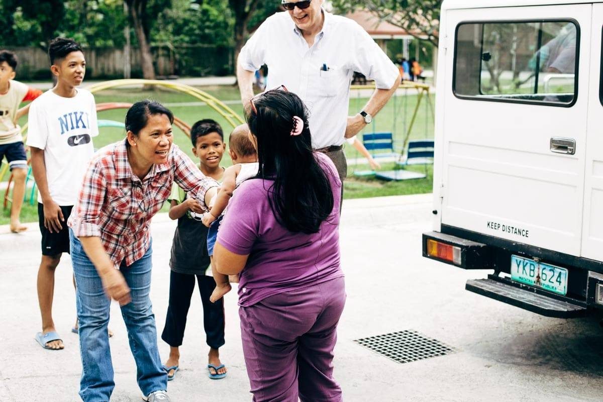 Woman holding a baby in a purple outfit.