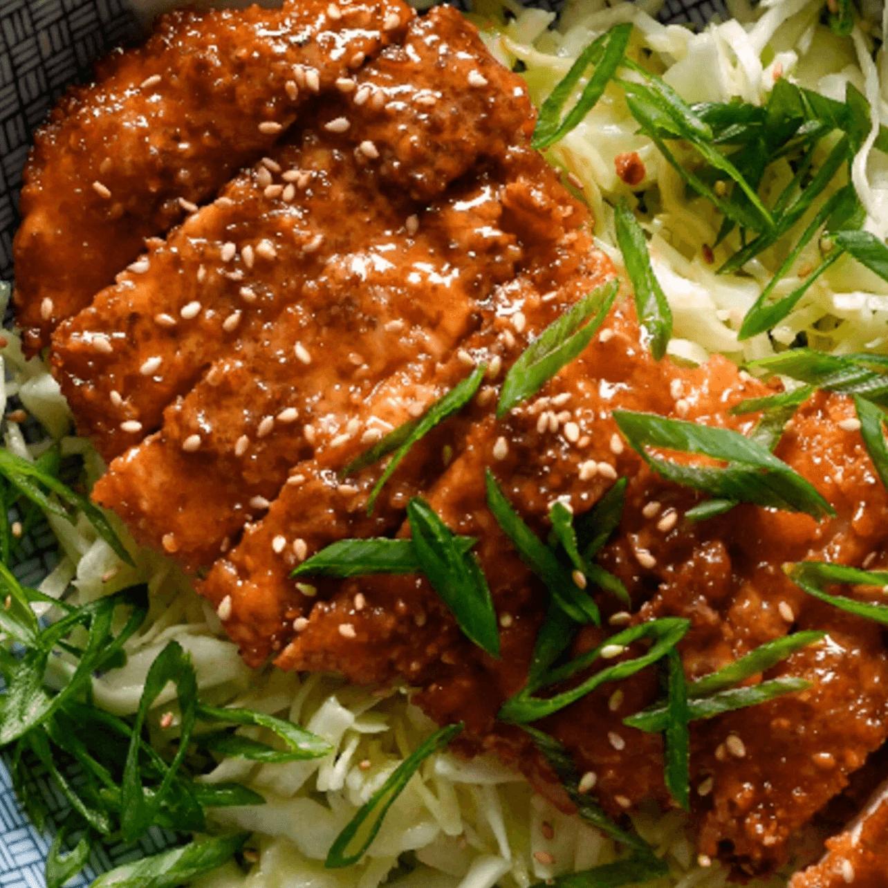 Crispy gochujang chicken on top of slaw.