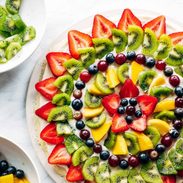 Fruit pizza with bowls of fruit.