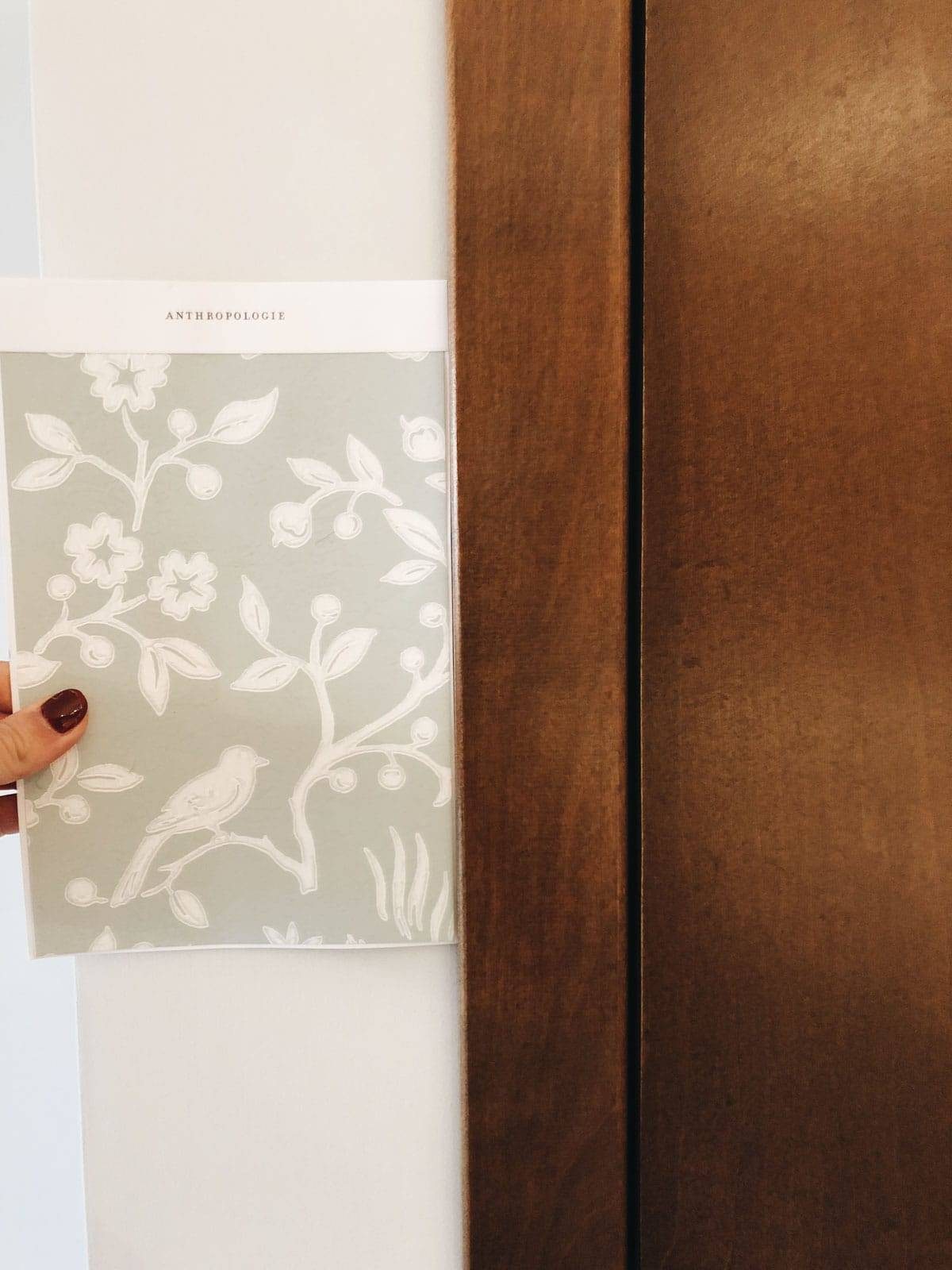 A hand holding a card with the word Anthropologie written on top of it.