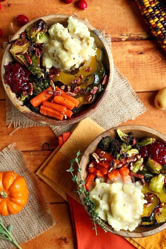Two Roasted Vegan Thanksgiving Bowls in wooden bowls on a wooden table