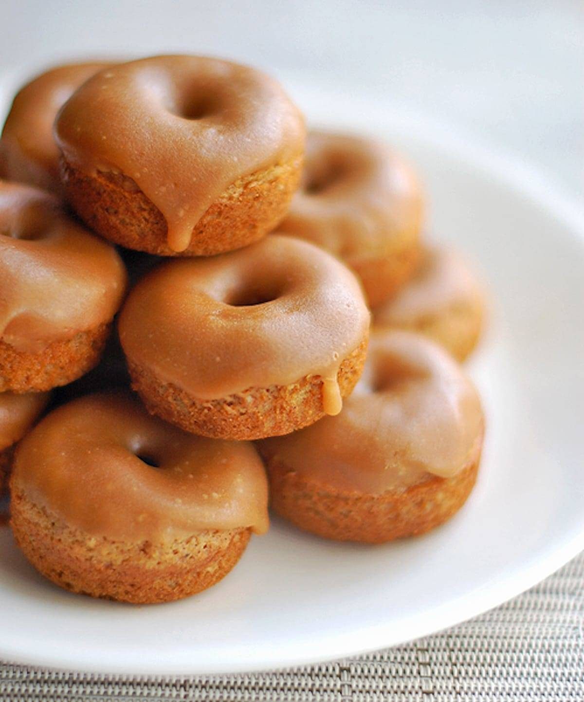 Baked Gingerbread Mini Donuts stacked on a white plate.